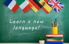 Learning languages concept - flags of Spain, France, Great Britain and other countries, blackboard with text "Learn a new language!", books and chancellery