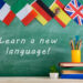 Learning languages concept - flags of Spain, France, Great Britain and other countries, blackboard with text 